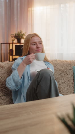 young woman drinking morning warm coffee at home sip refreshed look relaxed energy gold sunlight