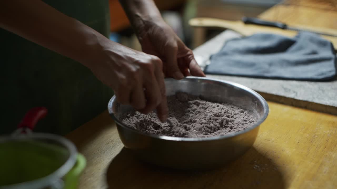 Mixture of chocolate powder and white flower being stirred with spoon in bowl on kitchen counter, filmed as close up slow motion shot