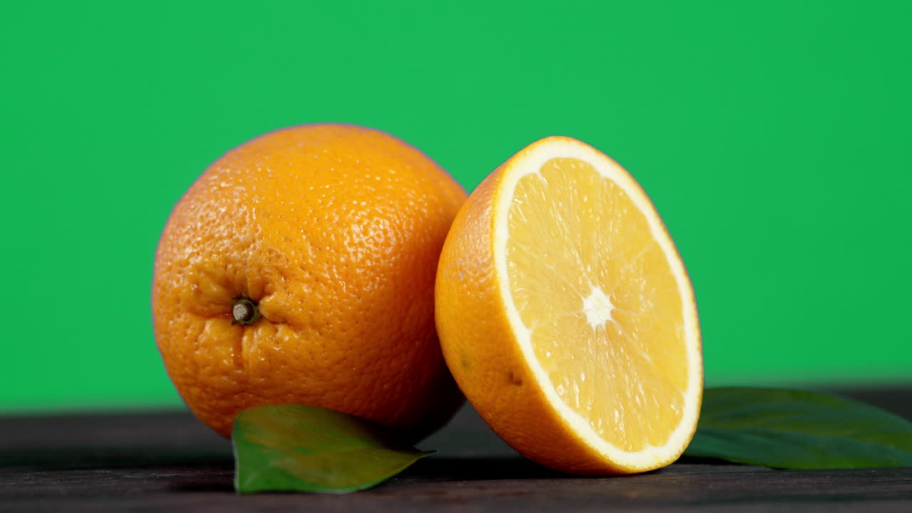 naranjas enteras y medias con hojas que giran lentamente.