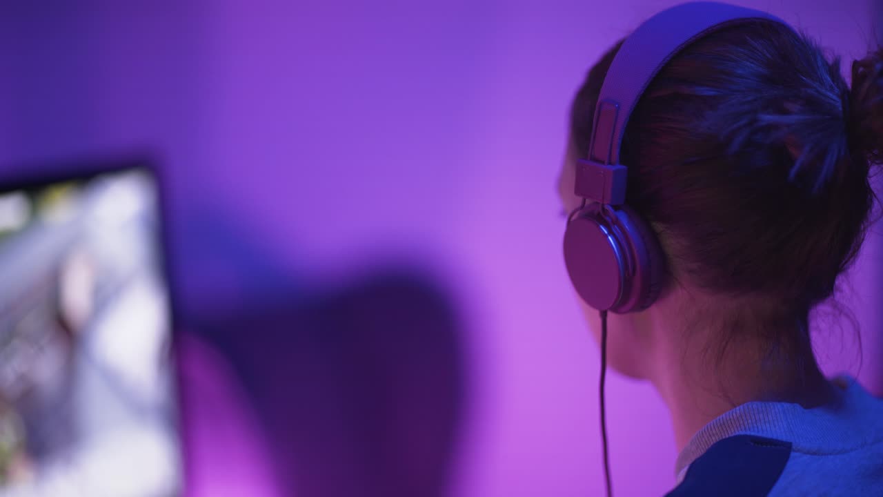 una foto de una jugadora profesional desde atrás a la izquierda jugando un videojuego en línea-4