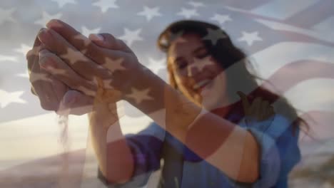 Animation-of-waving-flag-of-usa-over-woman-having-fun-on-the-beach