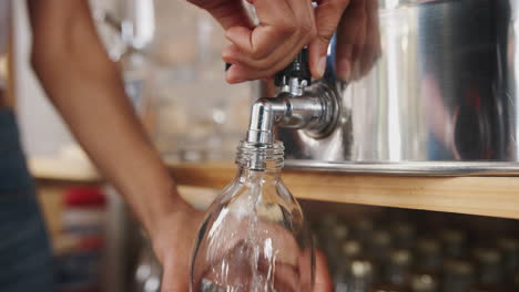 primer plano de una mujer llenando un recipiente con vinagre de sidra en una tienda de comestibles sostenible sin plástico