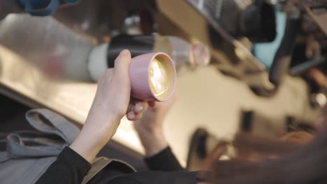 vertical, woman barista practices coffee drawing in kitchen classroom