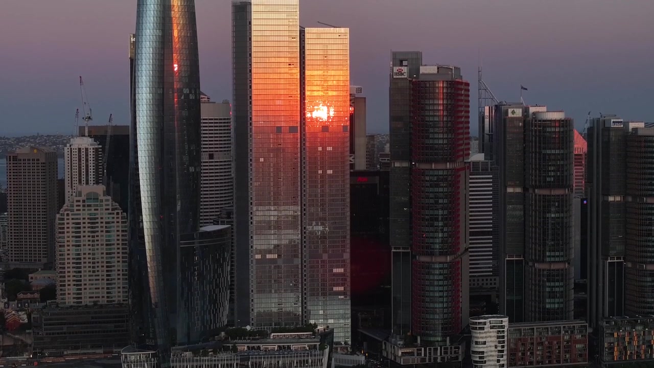 Reflexo do pôr do sol em arranha-céu alto em Darling Harbour, Sydney. Subida de drone tipo guindaste