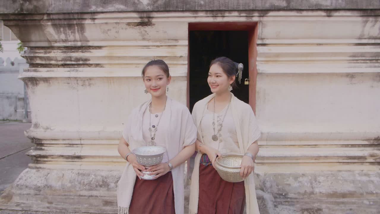 Two Young Women in Traditional Thai Clothing at a Temple