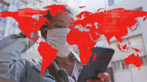 animation of world map showing infection over woman in face mask using smartphone in city