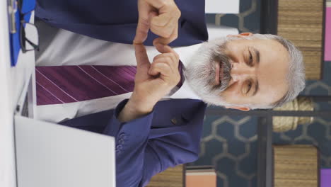 Vertical-video-of-Loving-old-businessman-making-heart-symbol-at-camera.