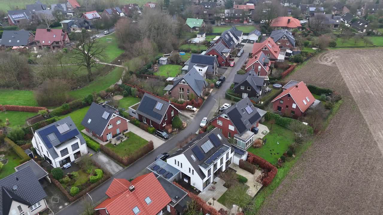 Modern american neighborhood with solar panels on rooftop during foggy winter day. Drone birds eye flyover. Single family homes in suburb district of USA. Agricultural farm fields in America.