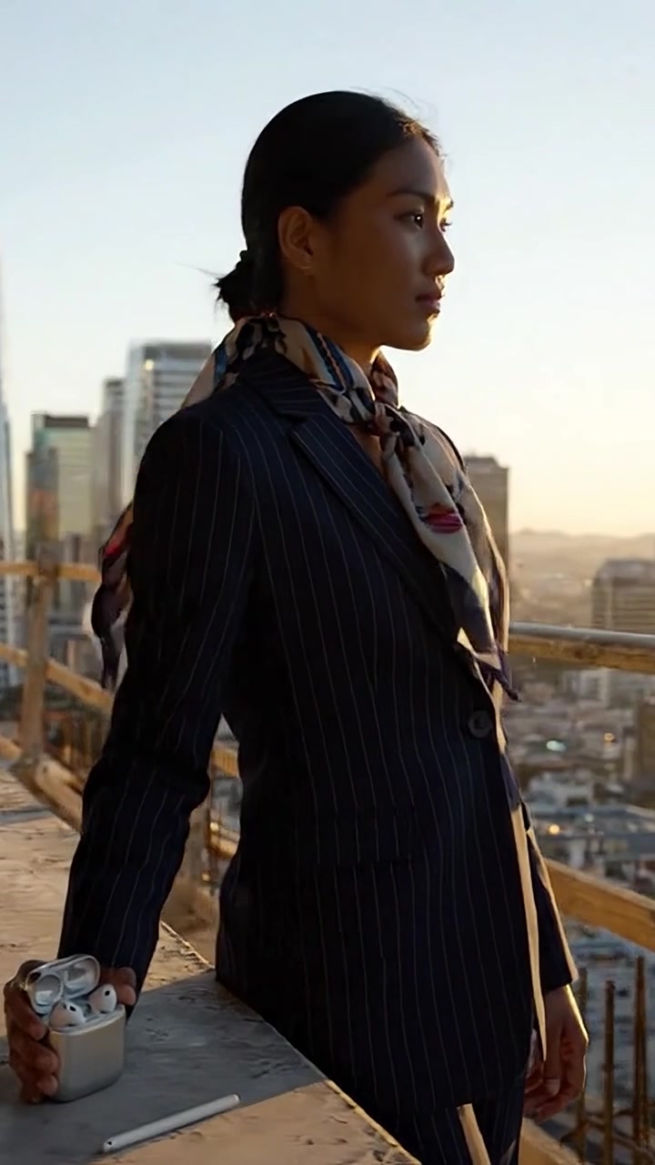 Uma Empresária Confiante Posa Contra o Horizonte da Cidade ao Pôr do Sol, Exibindo Elegância e Profissionalismo Enquanto Segura um Acessório Moderno em um Ambiente Sofisticado