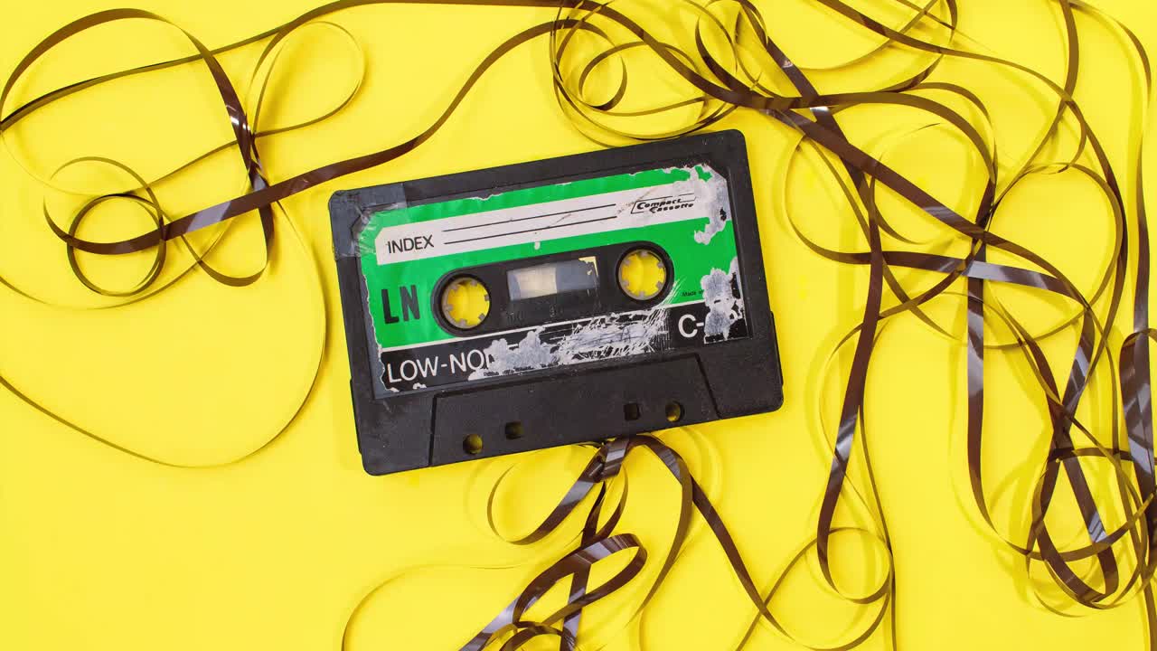 vieja cinta de casete retro con etiqueta grunge rebobinando la cinta tirada de la pila en el movimiento de parada de fondo amarillo
