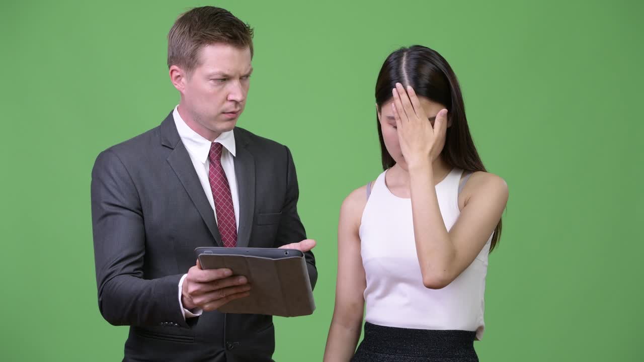 Young businessman showing bad news to young Asian businesswoman
