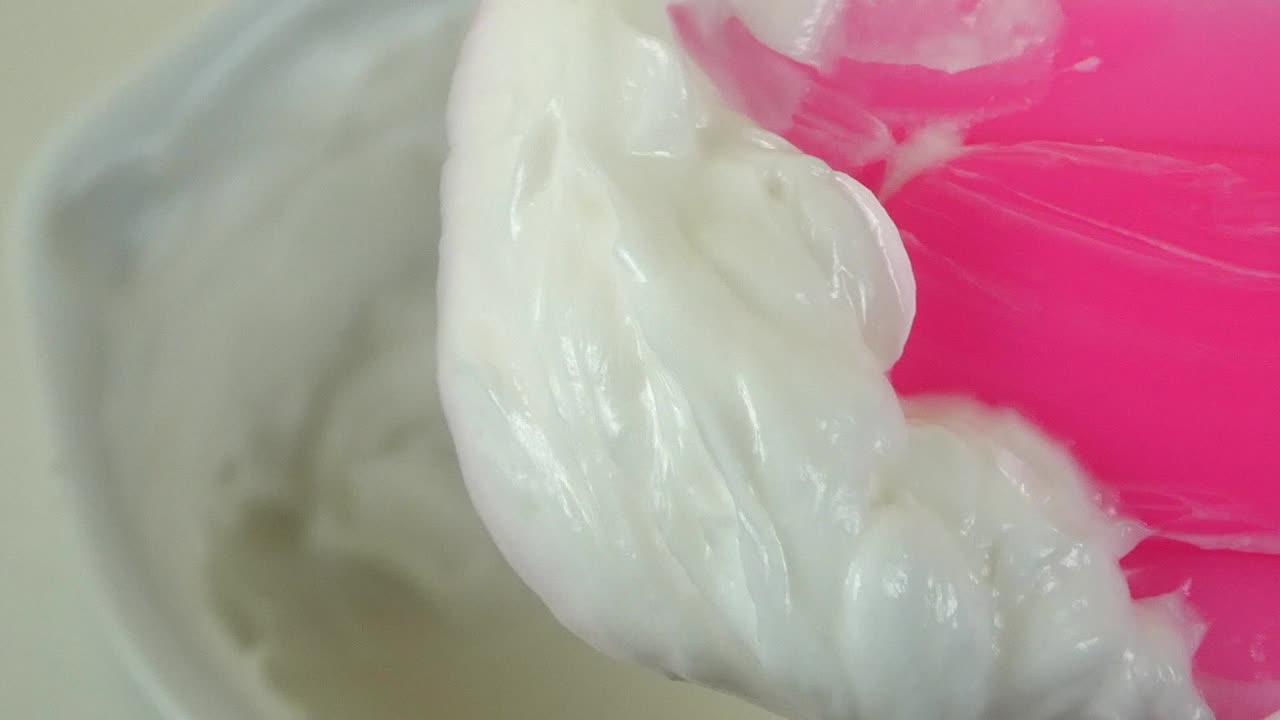 Macro shot of a cosmetic laboratory process where gloved hands in blue gloves mix a cream using a porcelain mortar and pestle.