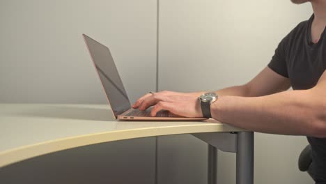 A-young-man-with-stubble-on-his-face-opens-up-his-rose-gold-colored-laptop-and-starts-his-daily-work-routine