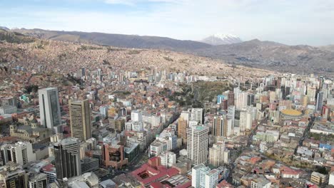 Die-Sich-Entfernende-Drohne-Enthüllt-Die-Faszinierende-Skyline-Von-La-Paz,-Elegant-Eingerahmt-Vom-Hoch-Aufragenden-Berg