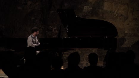 pan night time shot of a pianist performing for an audience