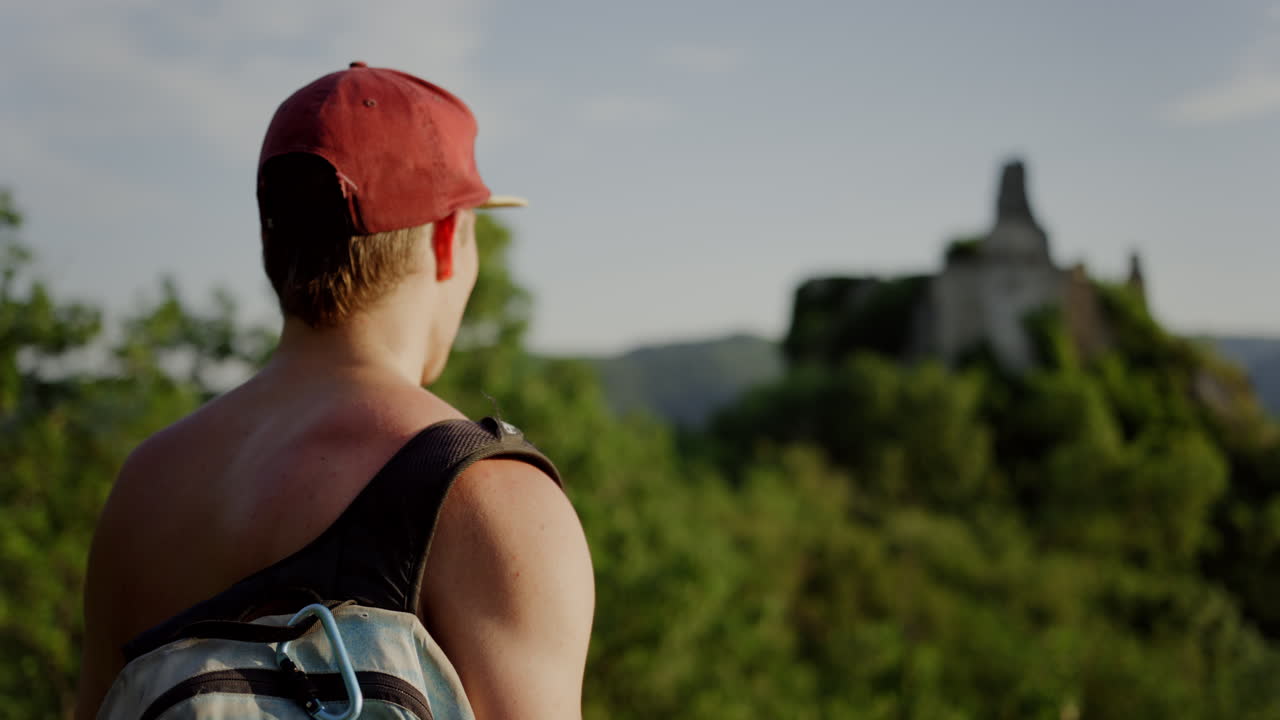 man looking over green mountain landscape, tourist Burgruine D&uuml;rnstein castle in the background, hiking trail, hills valley, hike trekking route Austria outdoor walking route, male person enjoying