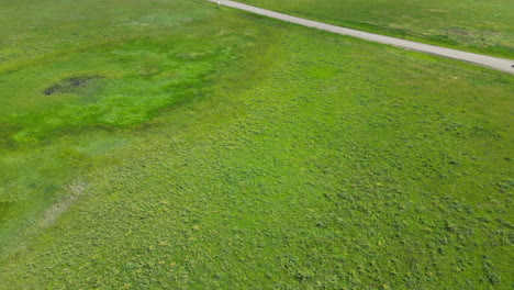 car turns on dirt road next to stunning green grass pastures