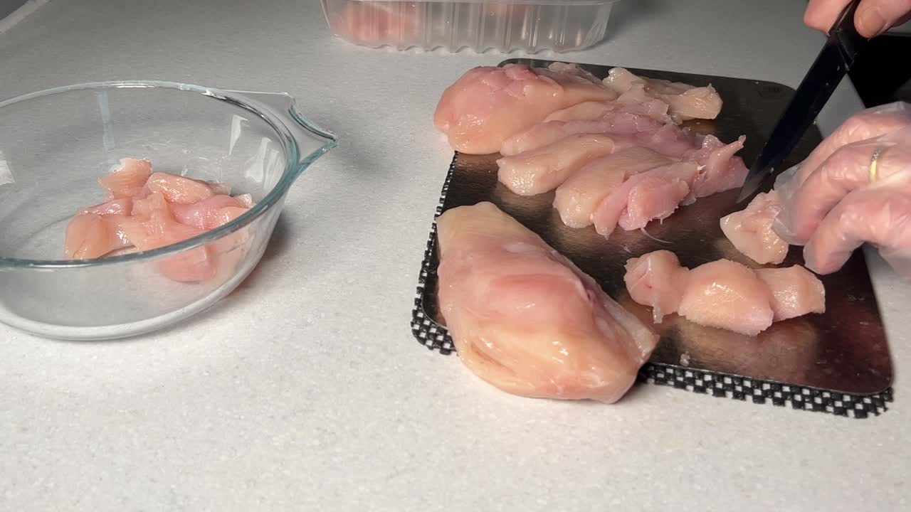 Female hands chopping up chicken on titanium board