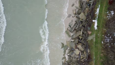 Vista-Aérea-De-Pájaro-De-La-Costa-Del-Mar-Báltico-En-Un-Día-De-Invierno-Nublado,-Bloques-De-Hormigón-En-La-Playa-Con-Arena-Blanca,-Erosión-Costera,-Cambios-Climáticos,-Amplia-Toma-De-Drones-Avanzando