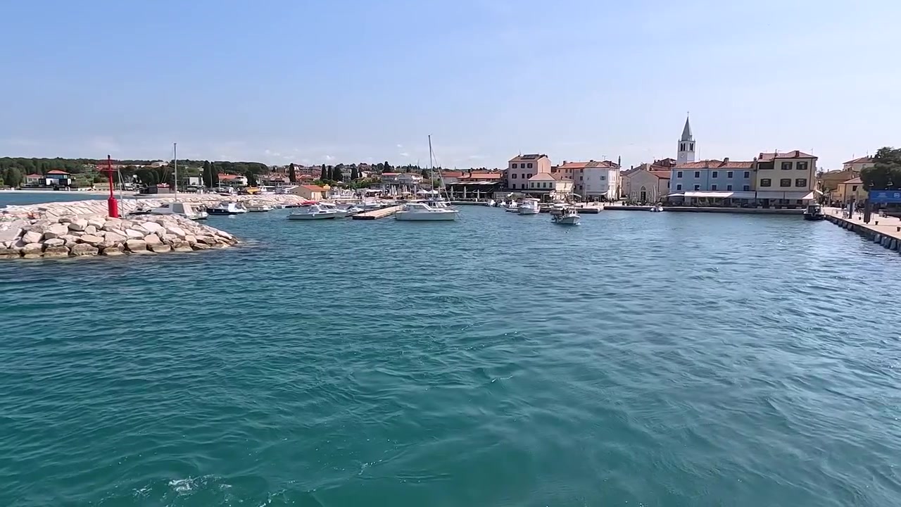 Pitoresk bir limandan manzaralı kıyı tekne kalkışı, turkuaz su ve tarihi köy mimarisi.