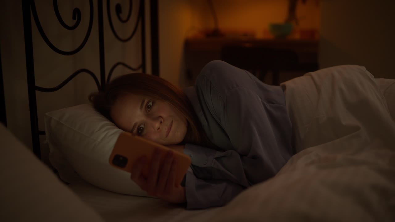 밤에 침대에서 드폰을 사용하는 여자