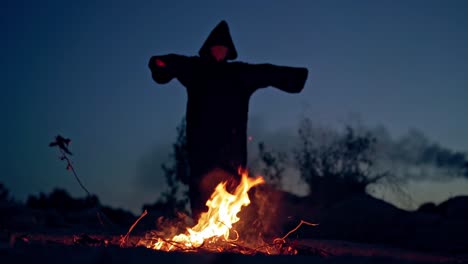 halloween. powerful witch or wizard stands by burning fire. black death at night. spooky atmosphere. nightmare near the fire flame.
