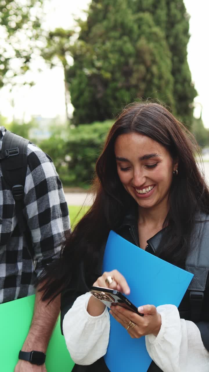 Jóvenes estudiantes felices caminando y hablando al aire libre con sus teléfonos