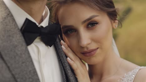 newlyweds, bride woman lying on her husband shoulder and looking at camera, happy wedding couple
