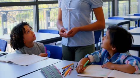 Glückliche-Schulkinder-Interagieren-Mit-Dem-Lehrer-Am-Schreibtisch-Im-Klassenzimmer-4k