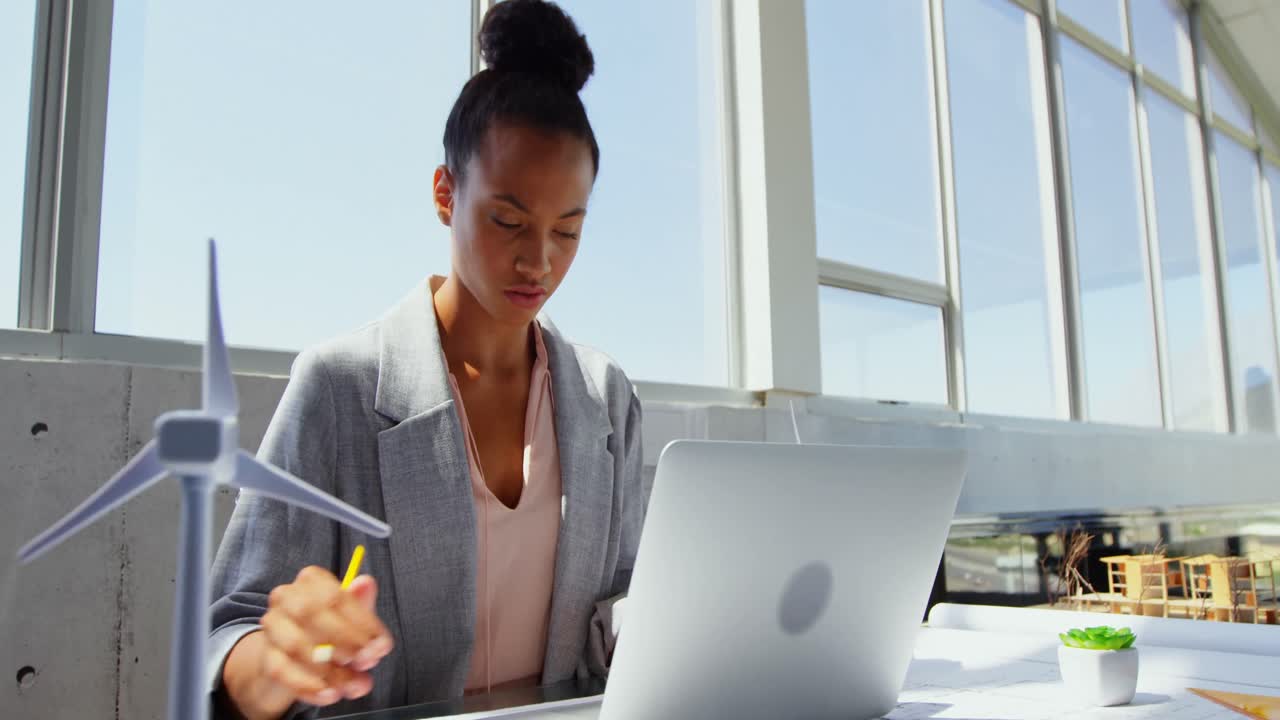 Front view of African American Businesswoman using laptop at desk in a modern office 4k
