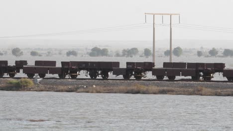 empty rail wagons on railway tracks with floodwaters either side in sindh with bird flying past