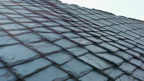 edificio con techo de piedras cortadas, moldeado y posicionado de manera geométrica para cubrir techos en áreas rurales - aéreo, de cerca