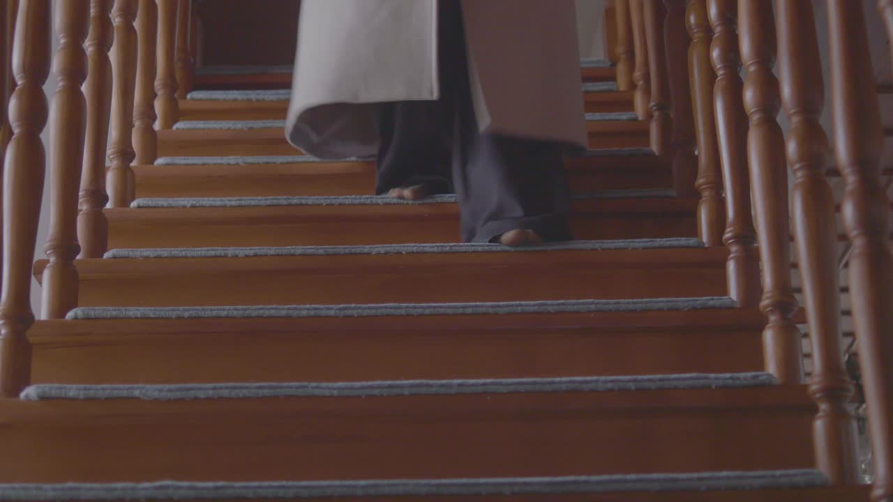 Person Walking Down Wooden Stairs with Carpet Strips