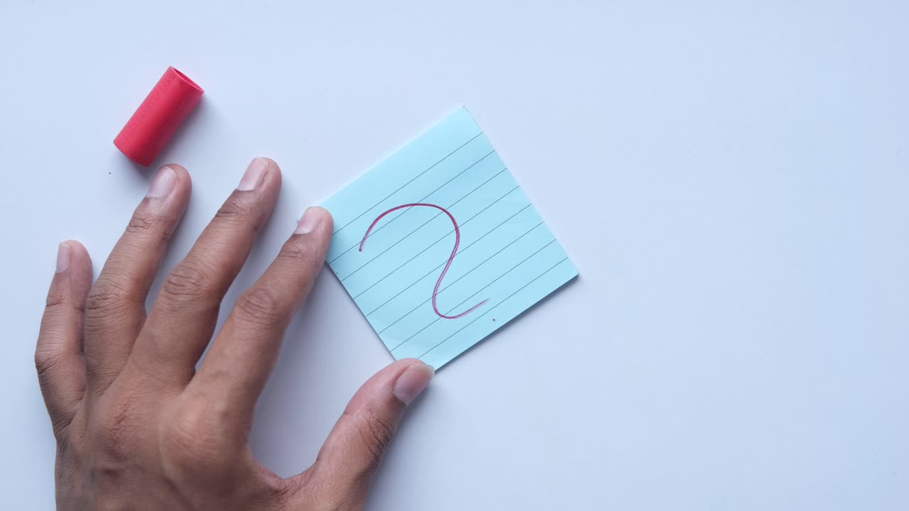Hand writing a question mark on a sticky note