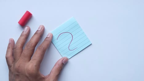 escribiendo a mano un signo de pregunta en una nota adhesiva