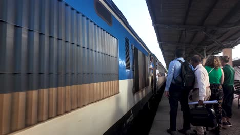 a train approaches the platform at kandy station surrounded by lush greenery in sri lanka. passengers wait eagerly, capturing a sense of travel and anticipation.