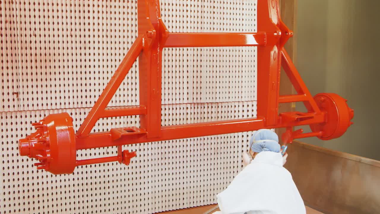 mujer pintando unidad industrial en rojo con pistola de pulverización. pintora trabajando