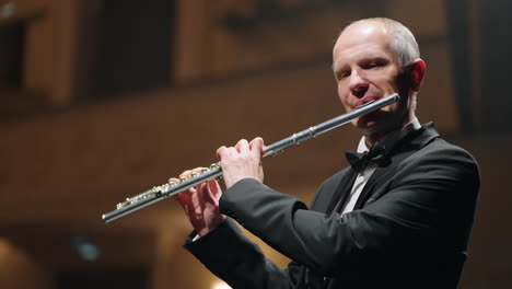 un hombre está tocando la flauta en un salón de música un músico en una orquesta sinfónica o una banda de vientos un concierto de música clásica