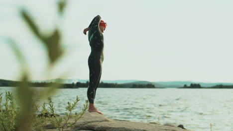 female triathlete stretching before swimming in lake