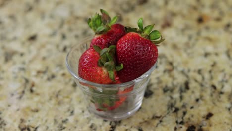 fresas guardadas en un pequeño cuenco de vidrio en una superficie de mármol