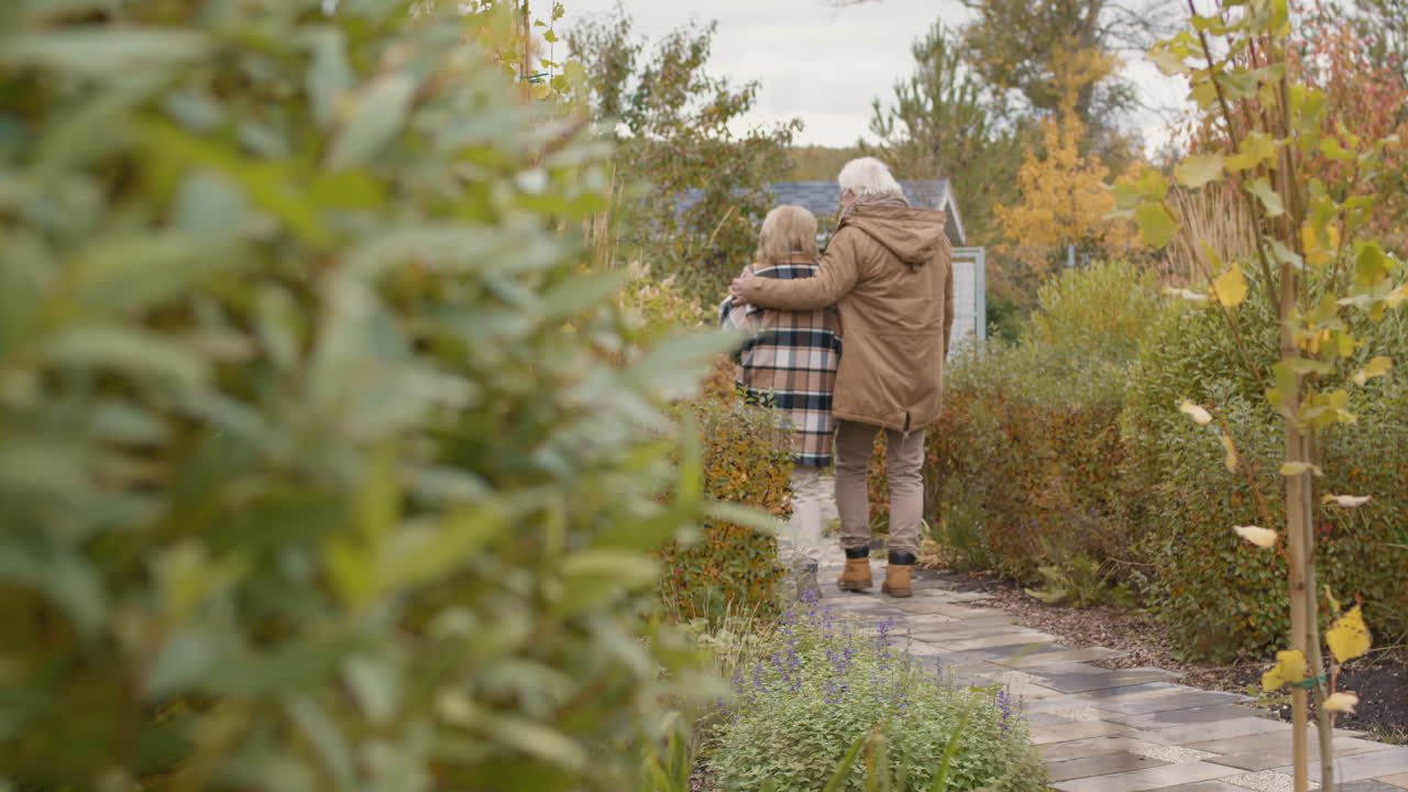 Elderly Couple Walking in Autumn Garden