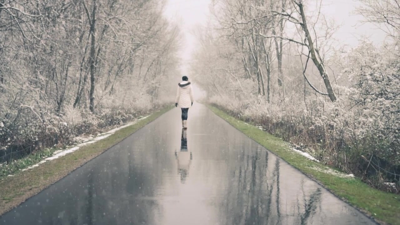 Donna che cammina su un sentiero bagnato in un paesaggio invernale innevato