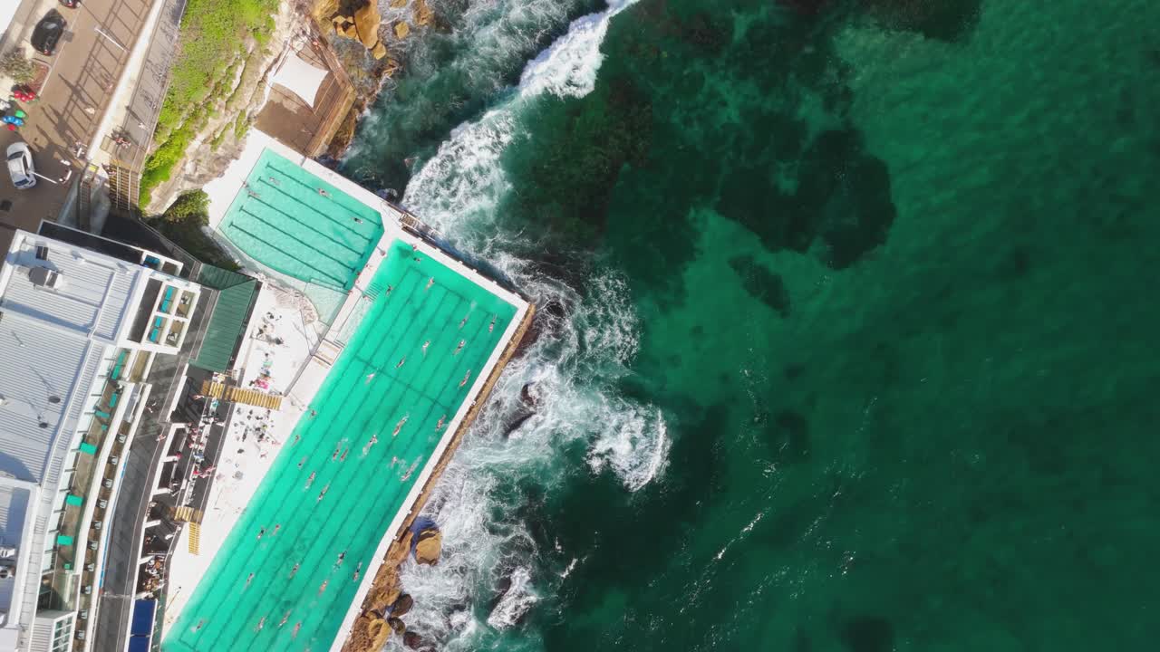 imágenes de drones de arriba hacia abajo de la piscina de los icebergs de bondi, rodeada de aguas oceánicas turquesas y olas estrelladas. la escena costera dinámica destaca la vibrante costa de sídney. capturada en 4k a 25 fps.