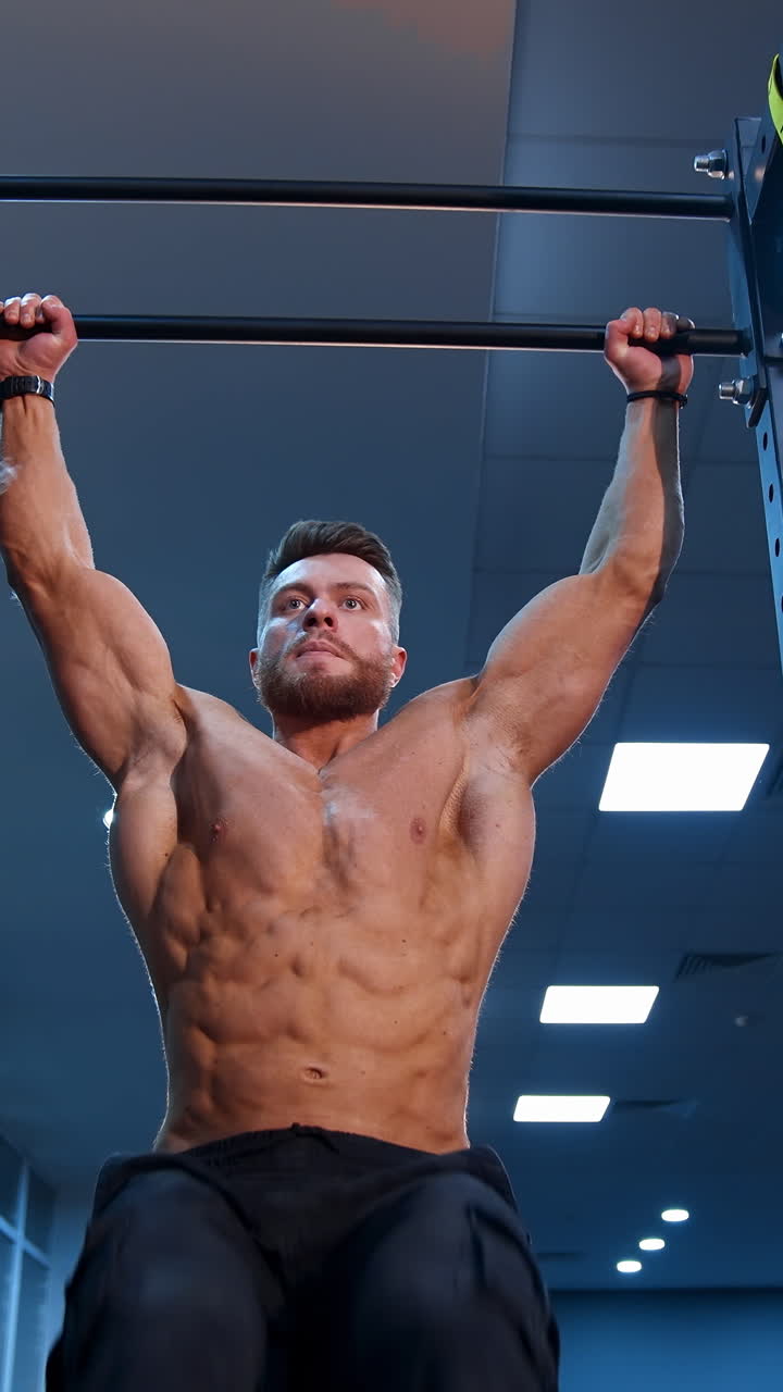 Man Performing Pull-Ups and Leg Raises in a Gym