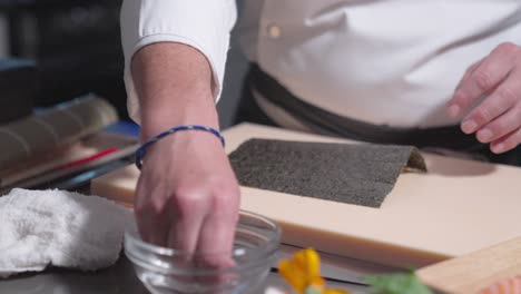 a roaming shot captures a sushi chef beginning the sushi-making process, showcasing the initial steps and technique involved. ideal for culinary, sushi preparation, and professional kitchen content.