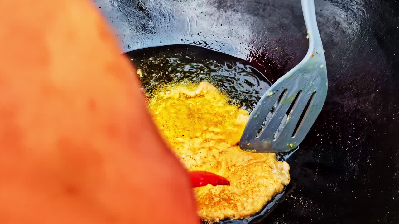Egg frying in a black pan, sizzling and bubbling with heat