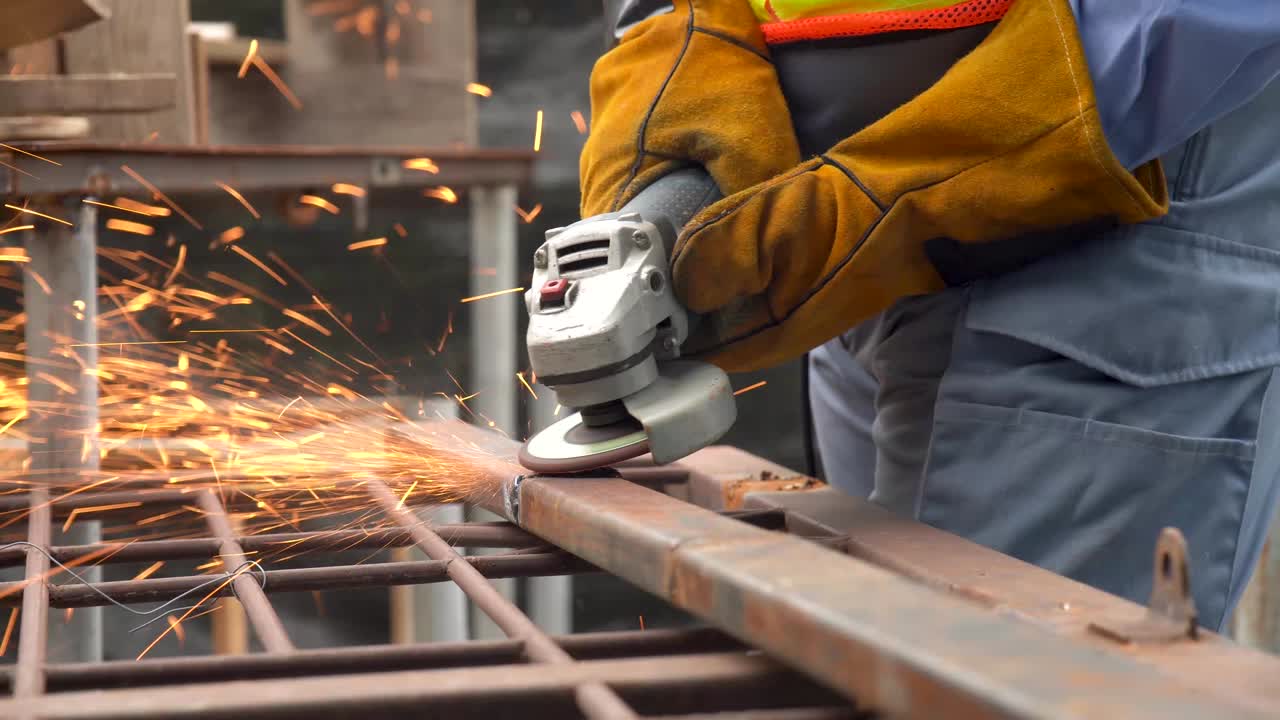 técnico industrial ingeniero en tela protectora usar máscara de seguridad, soldador usando un molinillo angular mientras trabaja en un taller industrial. chispas durante el corte de metal por un molino angular