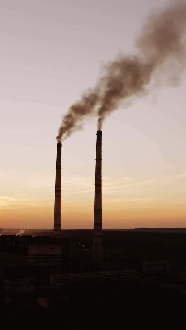 Highly polluting factory plant. Smoke from the pipes of plant at sunset Vertical video