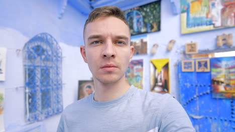 man taking selfie in a blue-painted moroccan art gallery