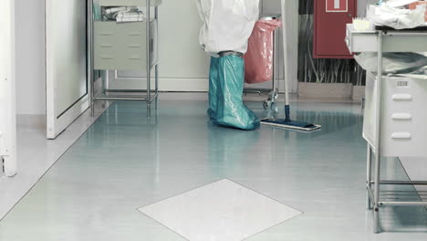 feet of hospital cleaner in full ppe mopping the tiled floor - medium shot